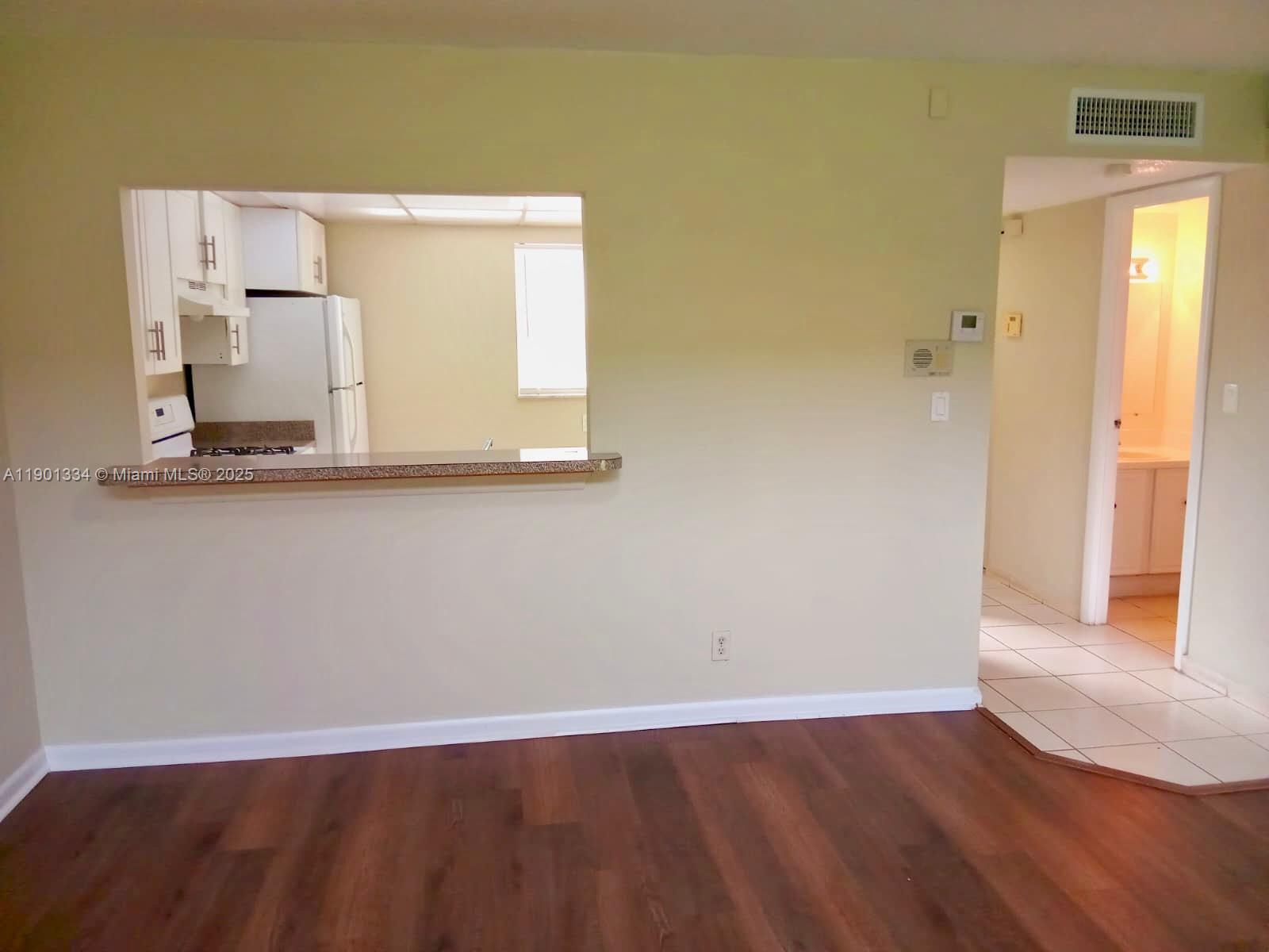 18051 Northwest 68th Avenue, Unit J102 Hialeah, FL 33015 - Photo 2 of 15 an empty room with wooden floor and a window