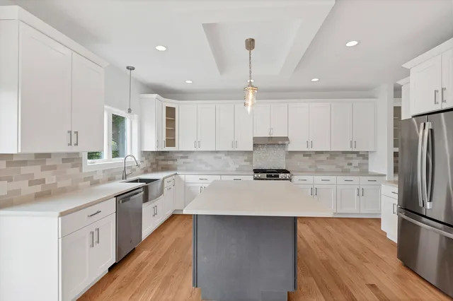 a kitchen with kitchen island granite countertop a sink a stove a counter space and cabinets