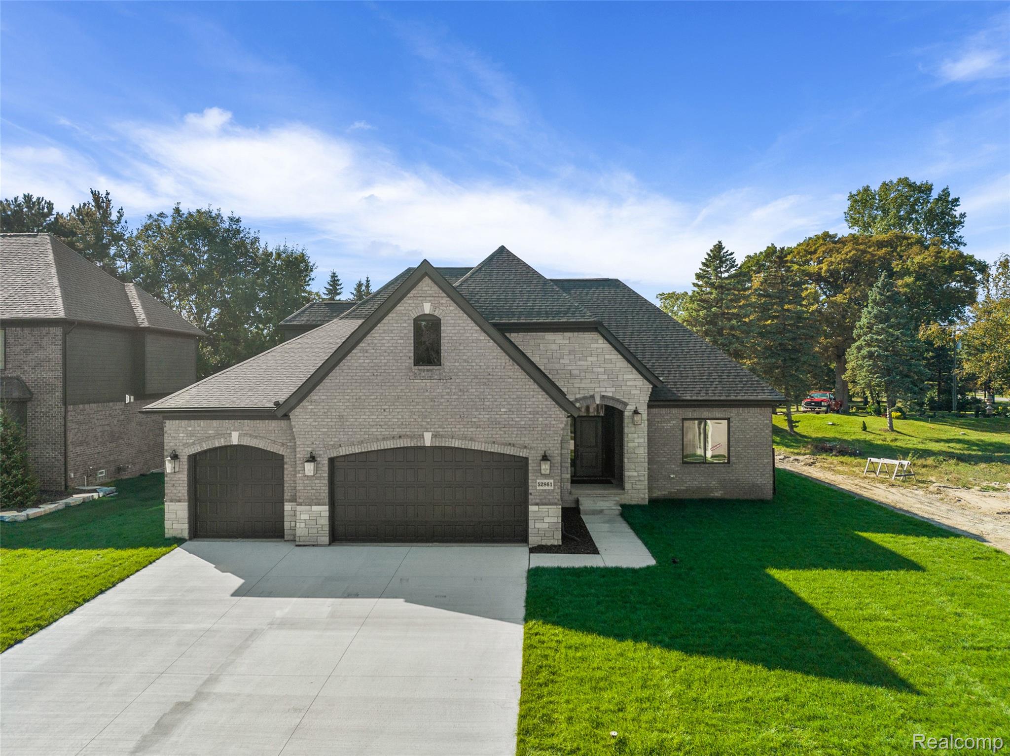 8267 Sandi Lane Romeo, MI 48065 - Photo 7 of 46 Brick and stone facade, dark asphalt shingle roofing, attached two-car garage, concrete driveway, and manicured lawn