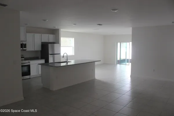 a kitchen with granite countertop a sink a counter top space and cabinets