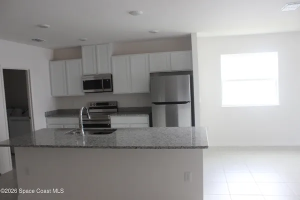 a kitchen with granite countertop a refrigerator and a sink
