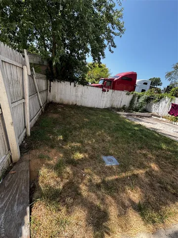 a view of a backyard with a tree and wooden fence