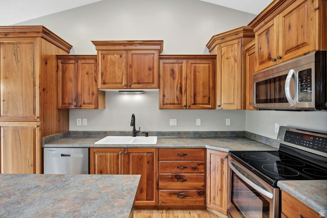 2912 South 1080th Street West Logan, UT 84321 - Photo 30 of 43 Kitchen featuring wood cabinetry, stainless steel appliances, a double basin sink, and wood-finish flooring