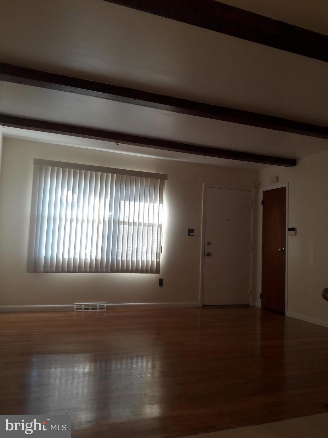 3113 Rheims Road Baltimore, MD 21244 - Photo 3 of 16 a view of an empty room with wooden floor and a window