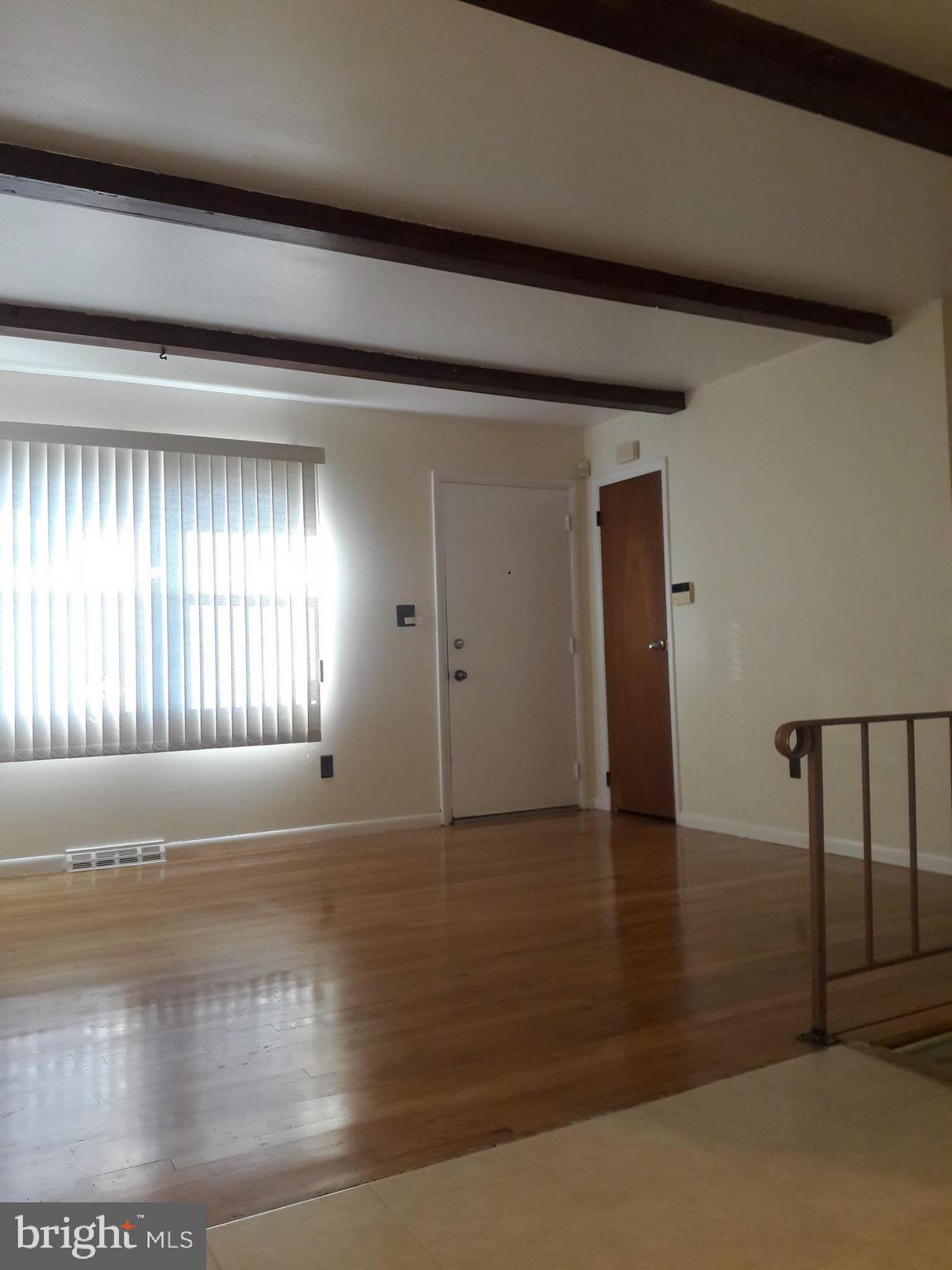 3113 Rheims Road Baltimore, MD 21244 - Photo 4 of 16 an empty room with wooden floor and windows with curtains