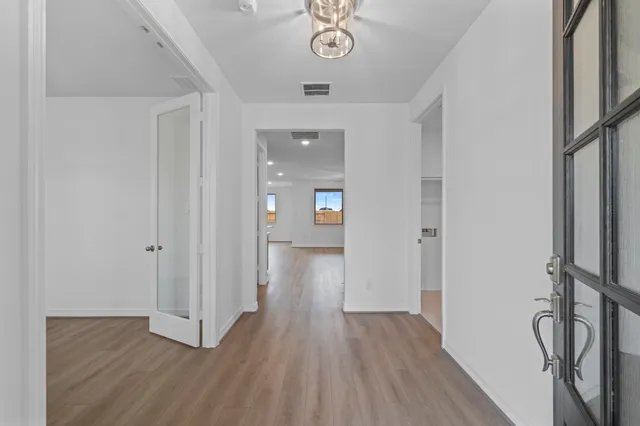 a view of an empty room with wooden floor and a window