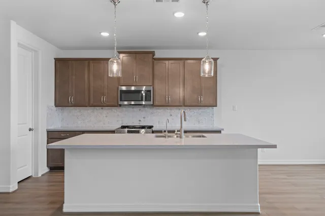 a kitchen with granite countertop stainless steel appliances a stove microwave and cabinets