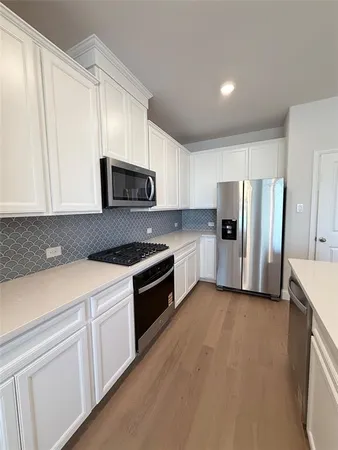 a kitchen with refrigerator a microwave a sink and cabinets