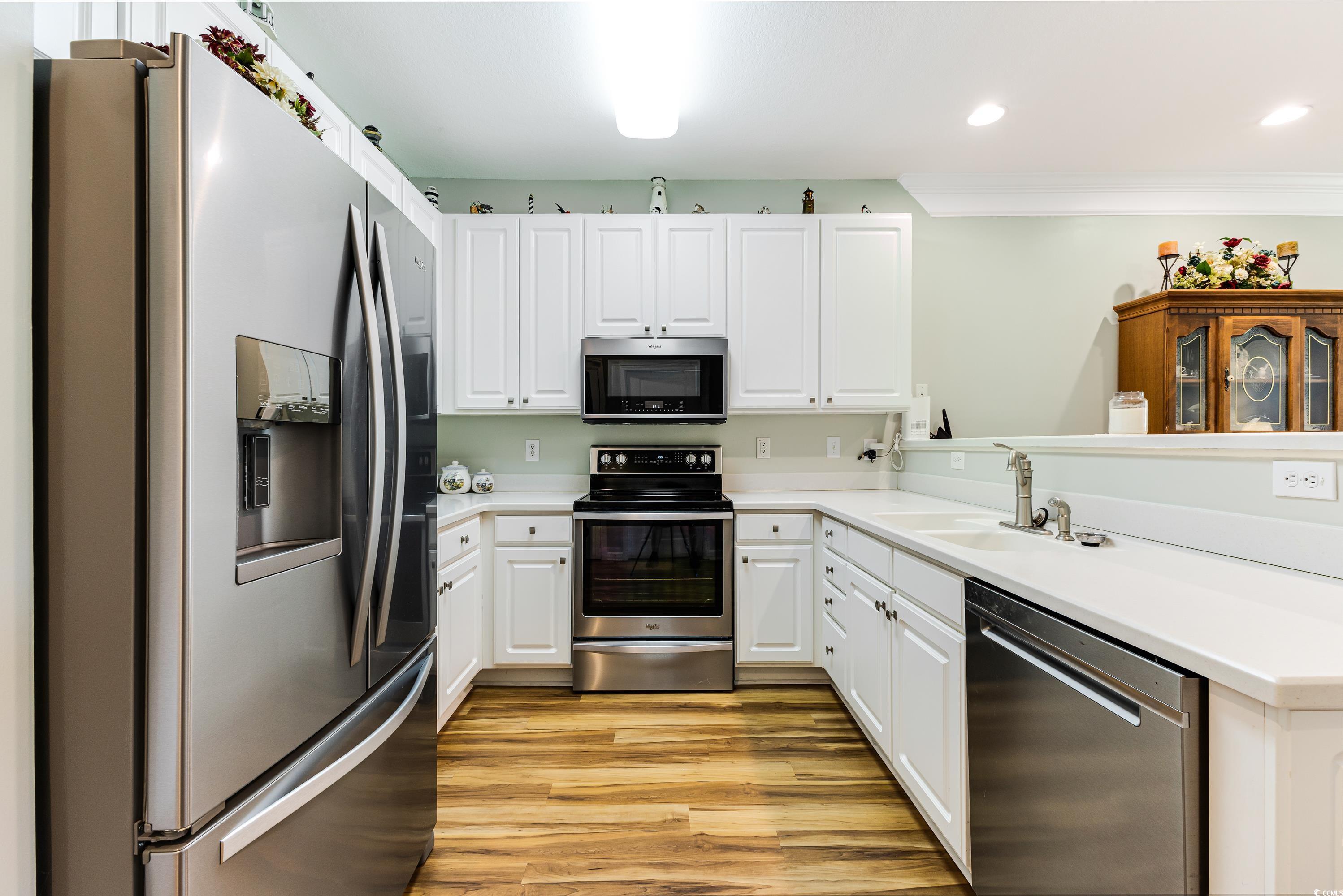260 Woodlands Way, Unit 2 Calabash, NC 28467 - Photo 6 of 40 Kitchen with stainless steel appliances, a sink, light wood-style flooring, a peninsula, and white cabinetry
