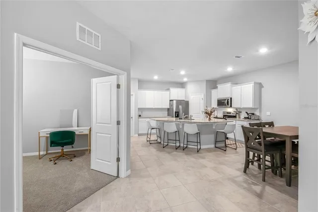 a kitchen with a dining table chairs and refrigerator