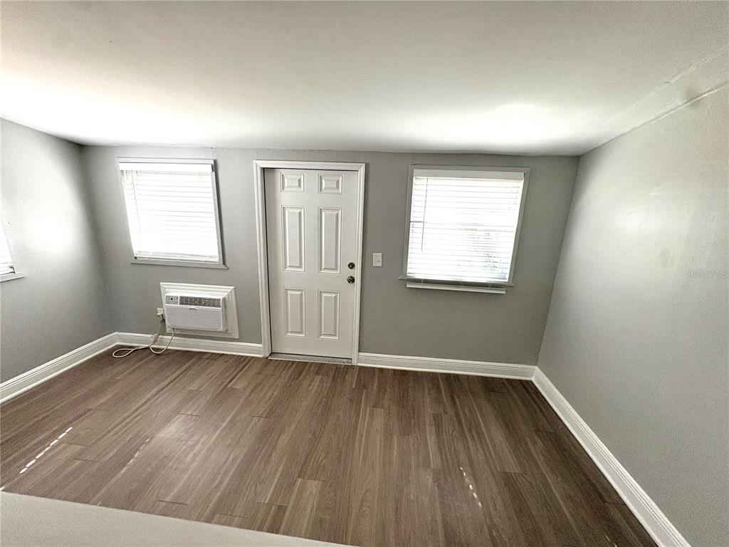 4611 North Hubert Avenue, Unit 11 Tampa, FL 33614 - Photo 3 of 10 an empty room with wooden floor and windows