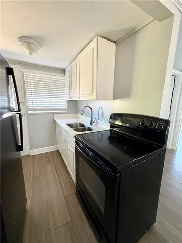 a kitchen with granite countertop stainless steel appliances a sink stove and cabinets