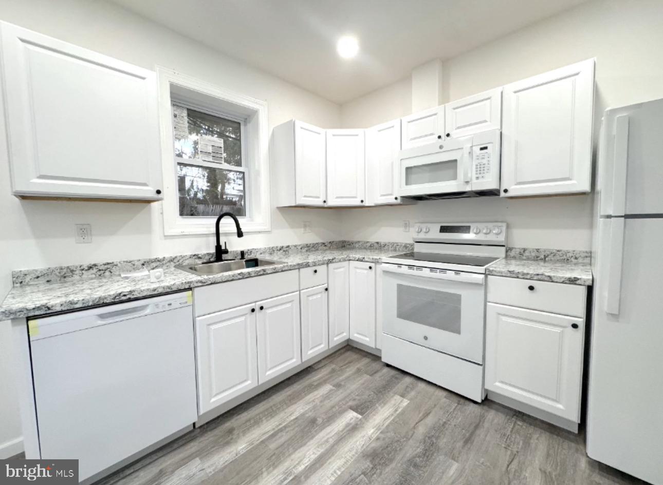2401 Carter Street Wilmington, DE 19802 - Photo 5 of 16 a kitchen with granite countertop white cabinets and white appliances
