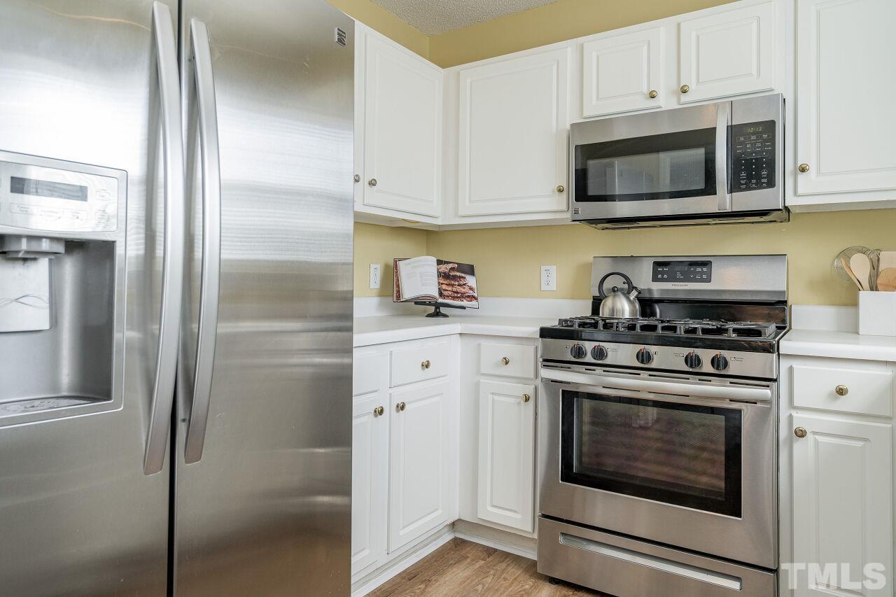 4428 Moss Spring Drive Raleigh, NC 27616 - Photo 12 of 27 a kitchen with stainless steel appliances granite countertop white cabinets a refrigerator and a stove top oven