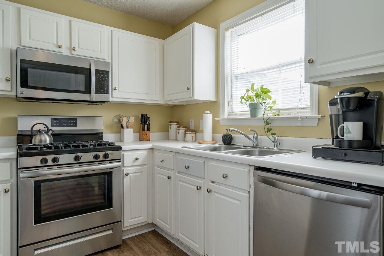 4428 Moss Spring Drive Raleigh, NC 27616 - Photo 14 of 27 a kitchen with stainless steel appliances granite countertop white cabinets a sink a stove a microwave and wooden cabinets