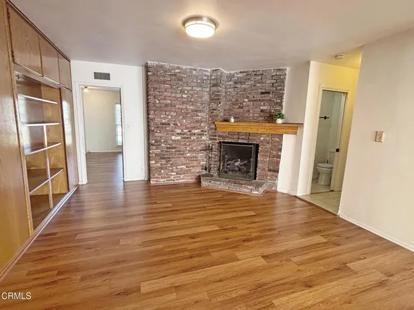 a view of a livingroom with wooden floor and a fireplace