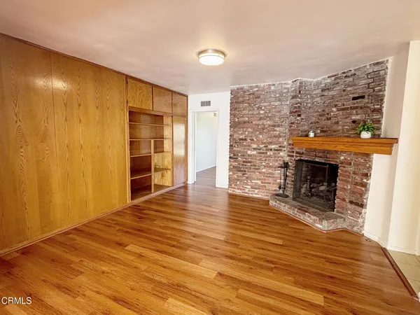 a view of empty room with wooden floor and fireplace