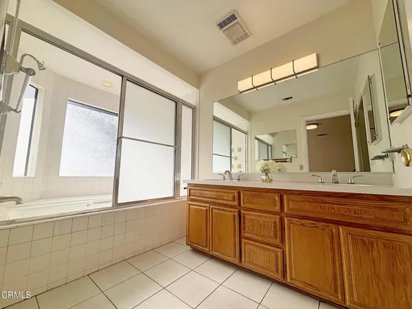 a bathroom with a sink mirror and a bathtub next to a window