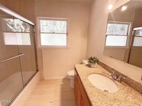 a bathroom with a granite countertop sink mirror vanity and a bathtub