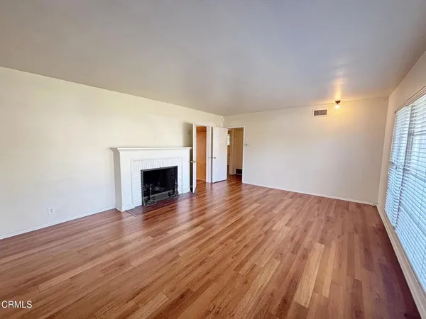 an empty room with wooden floor and fireplace