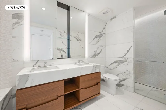 a bathroom with a sink toilet double vanity and shower