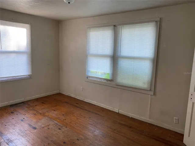 an empty room with wooden floor and windows