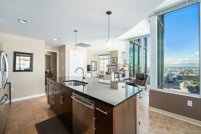 a kitchen with a sink a counter top space and living room view
