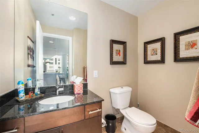 a bathroom with a granite countertop toilet a sink and a mirror