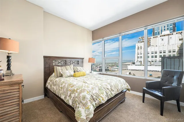 a bedroom with a bed chair and a large window