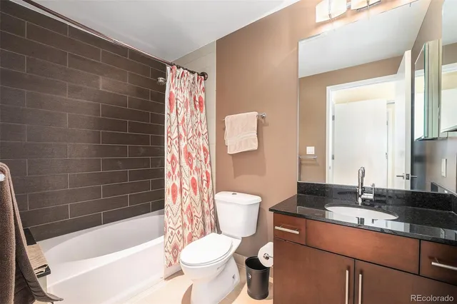 a bathroom with a granite countertop bathtub sink vanity mirror and toilet