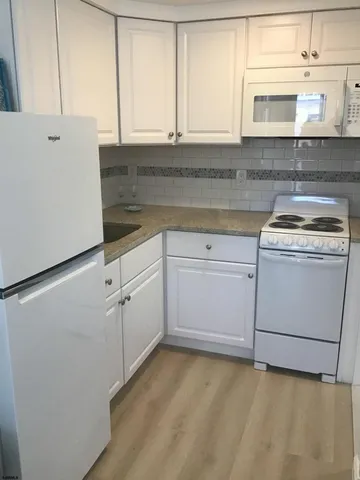 a kitchen with white cabinets and white appliances