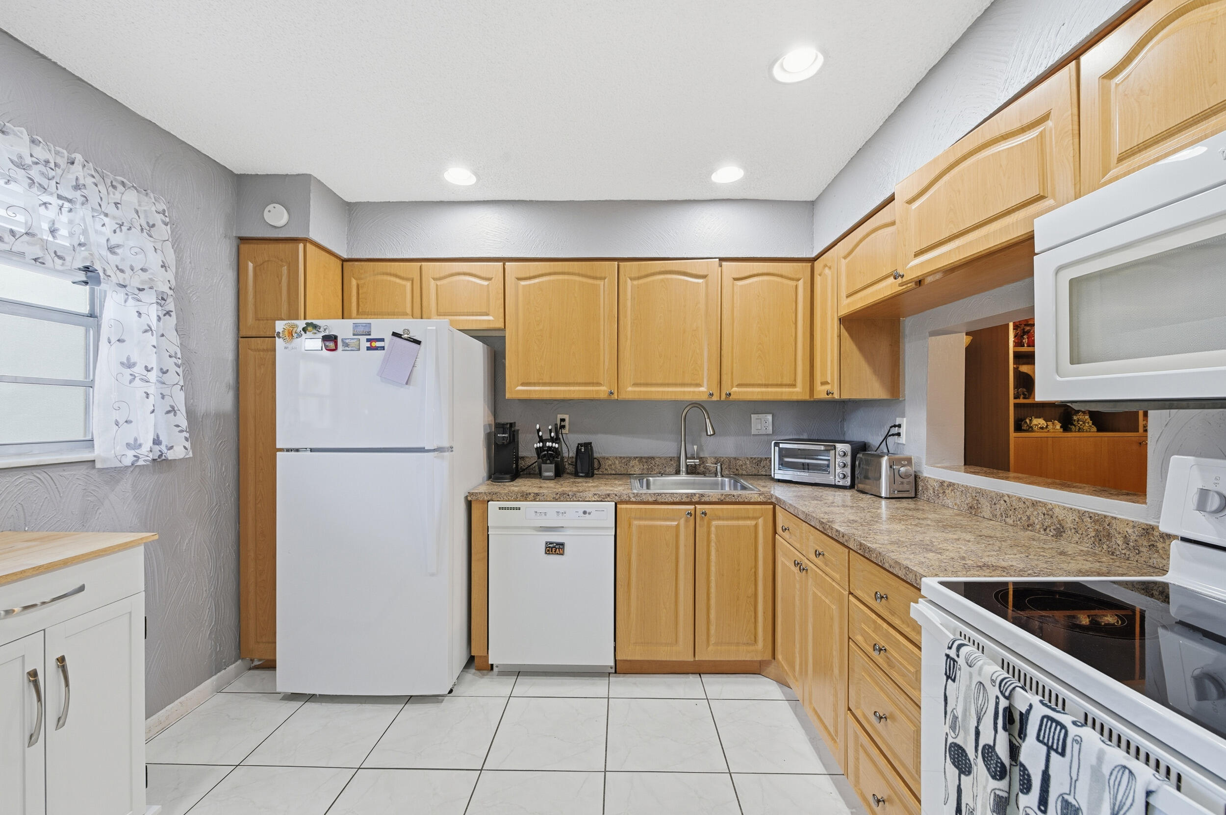 2600 Fiore Way, Unit 101C Delray Beach, FL 33445 - Photo 6 of 40 a kitchen with a refrigerator a stove a sink and cabinets