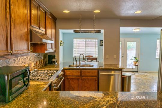 718 La Paloma Street Ridgecrest, CA 93555 - Photo 20 of 50 a kitchen with stainless steel appliances granite countertop a sink a stove and a wooden cabinets