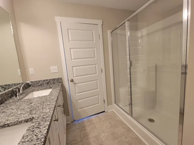a bathroom with a granite countertop sink and shower