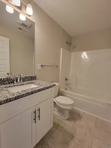 a bathroom with a granite countertop sink toilet mirror and a bathtub