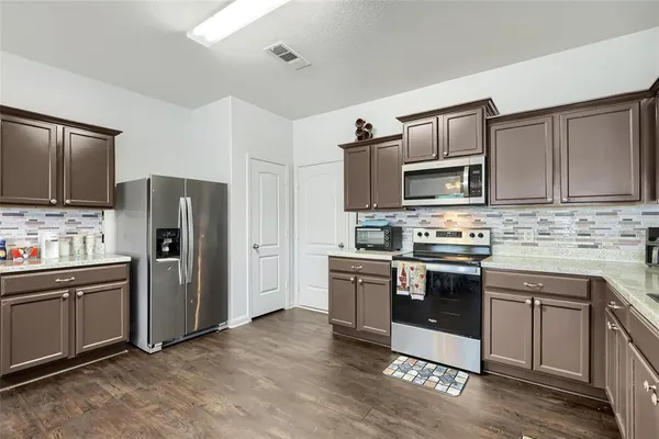 a kitchen with stainless steel appliances granite countertop a stove top oven a refrigerator and a sink