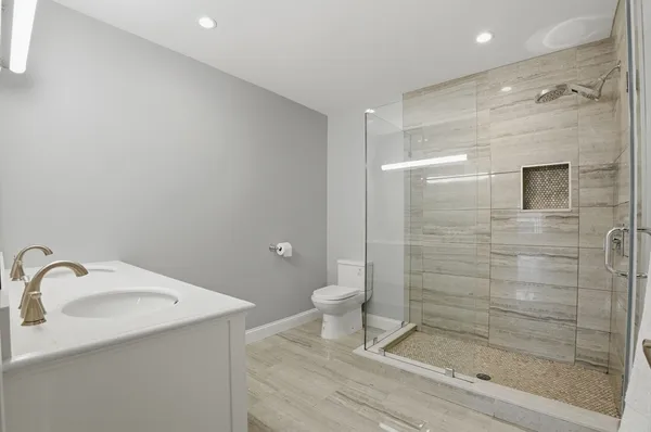 a bathroom with a granite countertop sink a toilet and shower