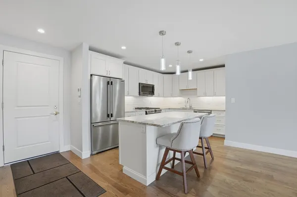 a kitchen with stainless steel appliances a dining table chairs refrigerator and sink