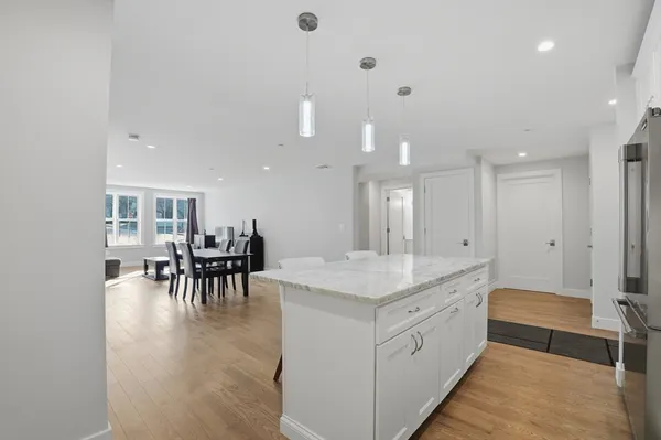 a large white kitchen with a large island oven and chairs
