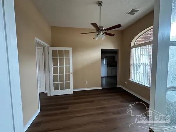 a view of an empty room with wooden floor and a window