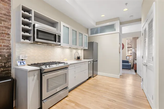 a kitchen with stainless steel appliances white cabinets and a stove top oven