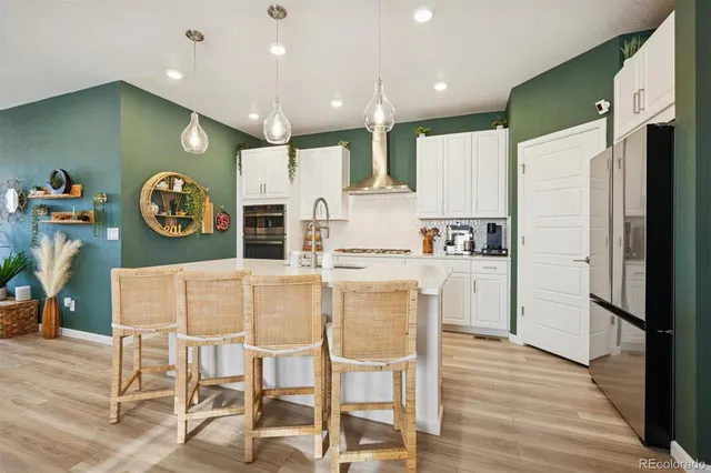 a kitchen with stainless steel appliances granite countertop a refrigerator a stove top oven and a dining table with wooden floor