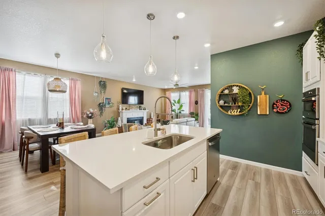 a view of kitchen island a sink and a stove top oven with wooden floor