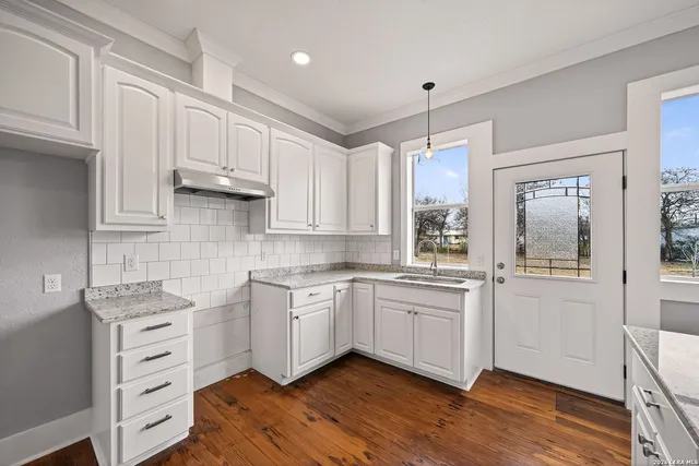 a kitchen with granite countertop white cabinets and white appliances