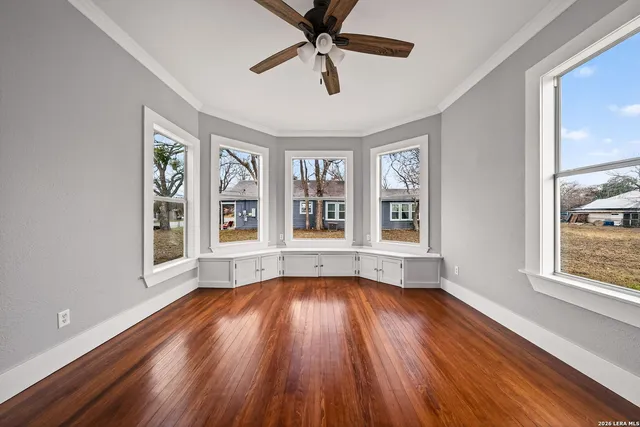 a view of an empty room with wooden floor and a window
