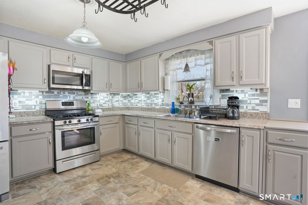 111 Ione Drive Meriden, CT 06450 - Photo 4 of 37 a kitchen with granite countertop a stove a sink and a microwave