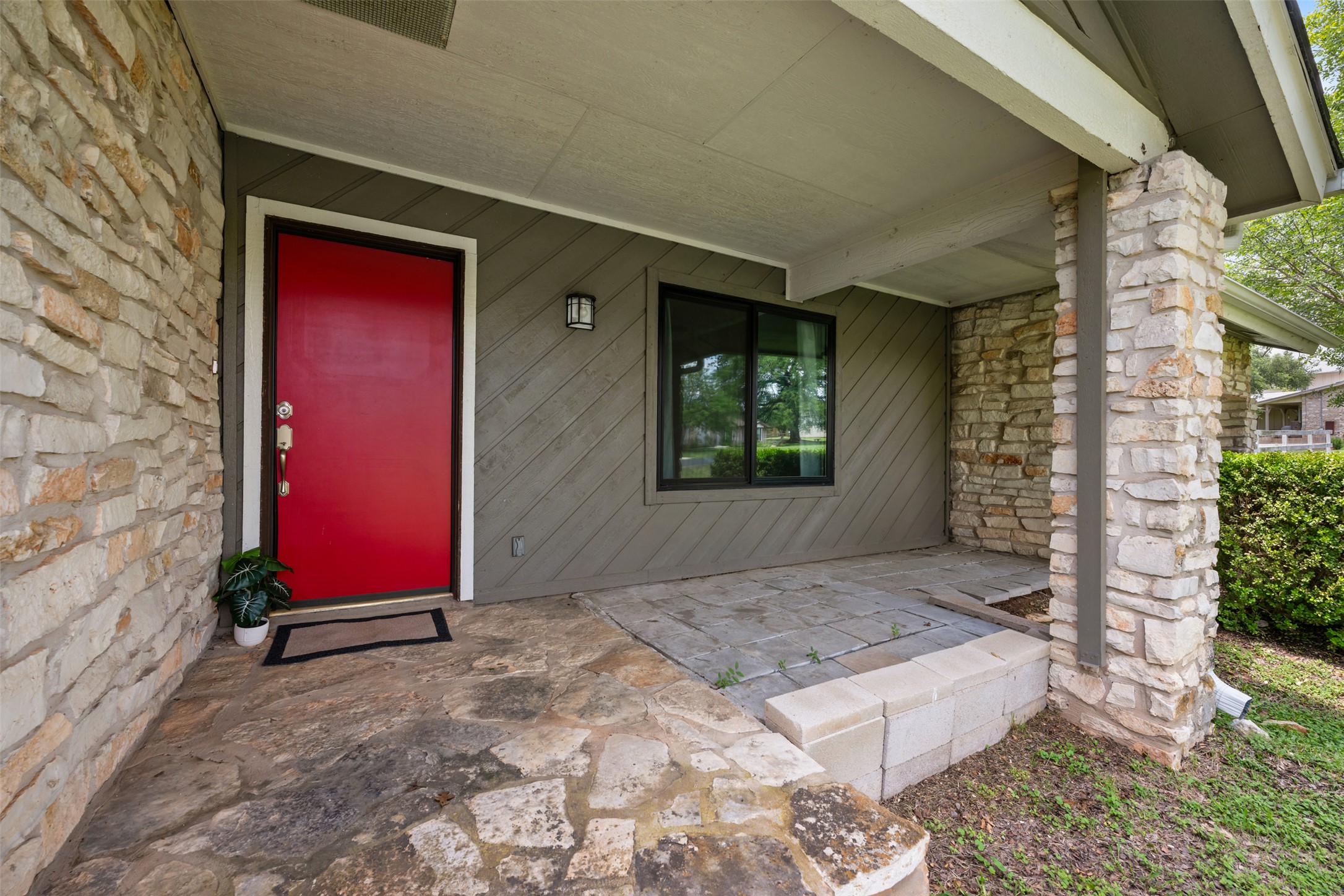 1600 Pin Oak Lane Round Rock, TX 78681 - Photo 3 of 40 Stone veneer exterior with a contrasting red entry door and a covered front porch featuring flagstone flooring