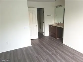 a view of a hallway with wooden floor and a bathroom