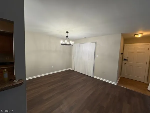 an empty room with wooden floor a chandelier and windows