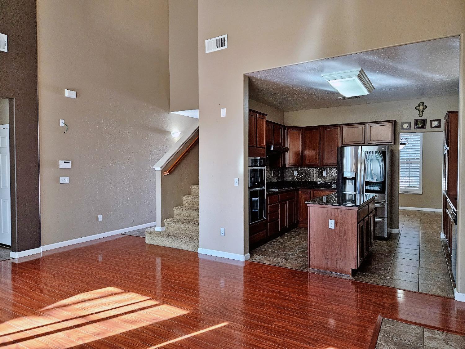 828 Tureaud Lane Clovis, CA 93619 - Photo 12 of 24 a kitchen with stainless steel appliances granite countertop a refrigerator a sink dishwasher a stove and a dining table with wooden floor